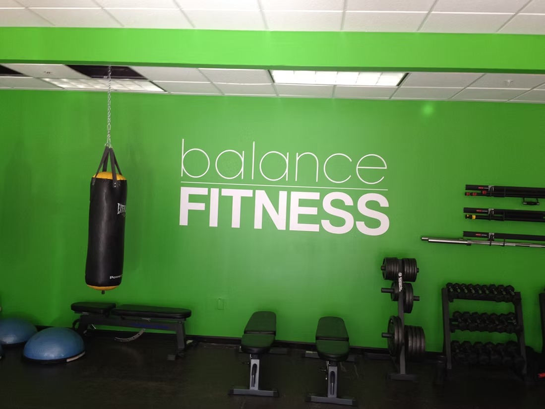 White Balance Fitness lettering installed on a green gym wall